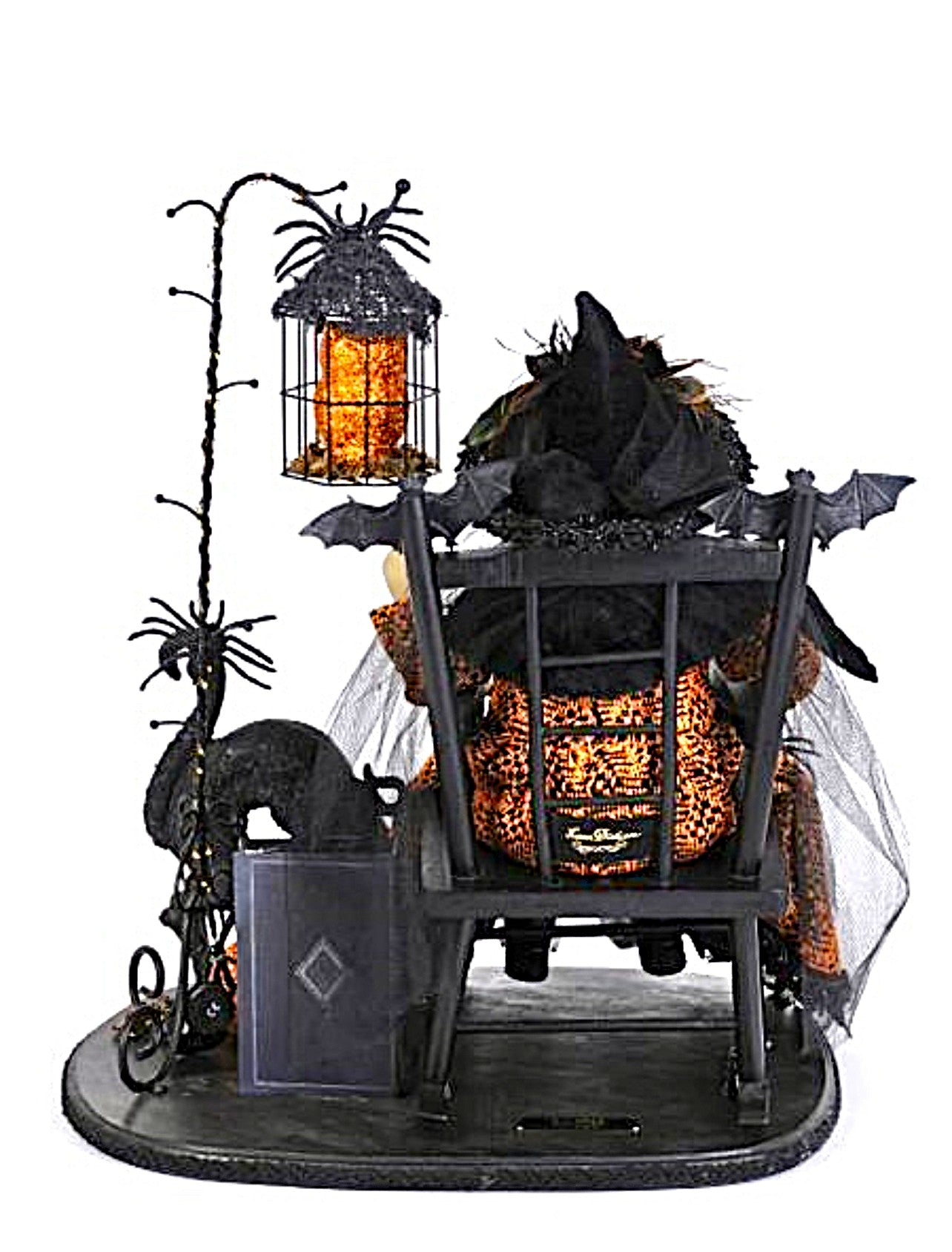 Halloween-themed decorative scene with a witch in a chair, pumpkins, and a spider web.