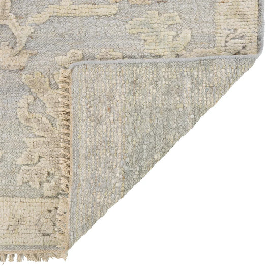 Corner of a textured rug with fringe on a white background