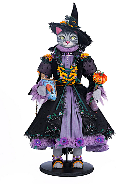 Cat dressed as a witch with Halloween-themed accessories on a white background