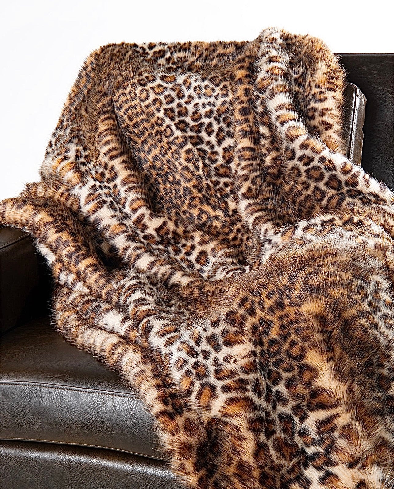 A leopard faux fur throw draped over a couch, showcasing its plush texture and animal print pattern.