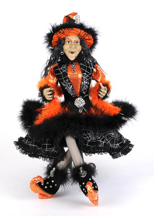 Halloween-themed doll in black and orange outfit with spider web details on a white background