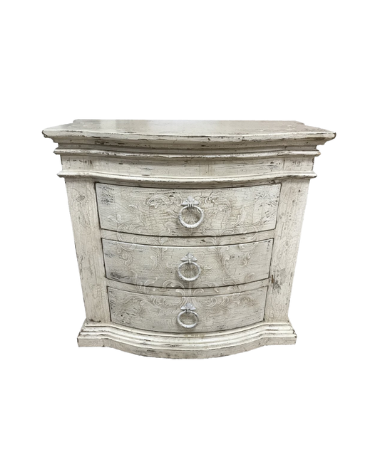 A distressed white wooden chest of drawers with three drawers and round metal ring pulls, shown against a plain white background.